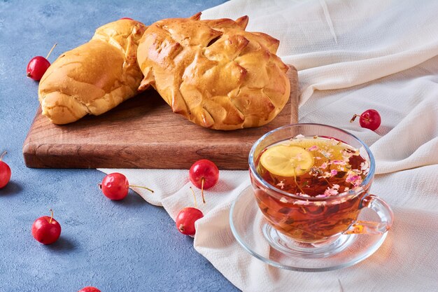 Pastry buns with herbal tea on a wooden board on blue