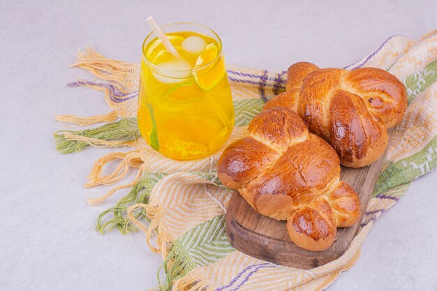 Pastry buns on a wooden board with a glass of lemonade