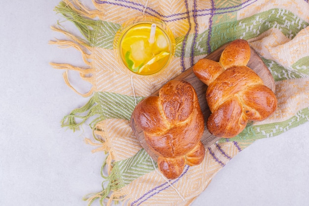 Pastry buns on a wooden board with a glass of lemonade