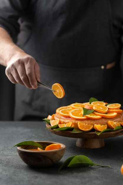 Pastry chef putting orange slices on cake