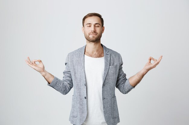 Patient and calm bearded guy meditating with closed eyes