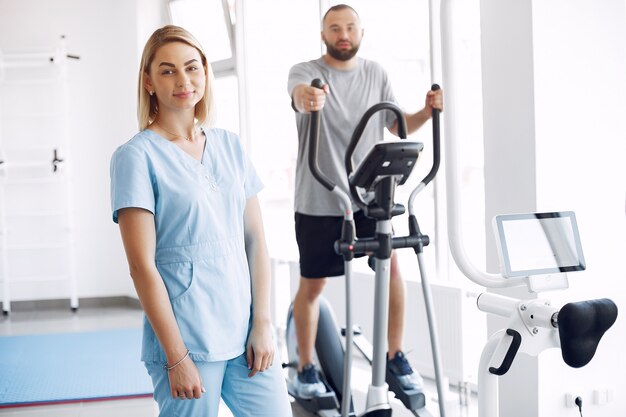 Patient doing exercise on spin bike in gym with therapist