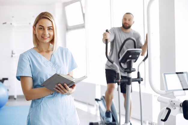 Пациент делает упражнения на велотренажере в тренажерном зале с терапевтом