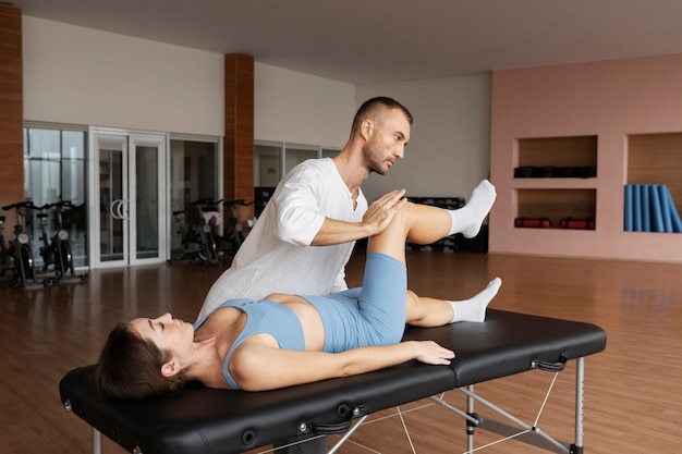 Patient doing physical rehabilitation helped by therapists