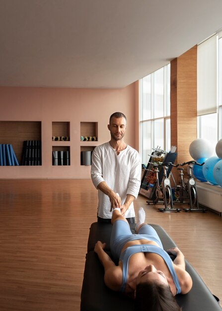 Patient doing physical rehabilitation helped by therapists