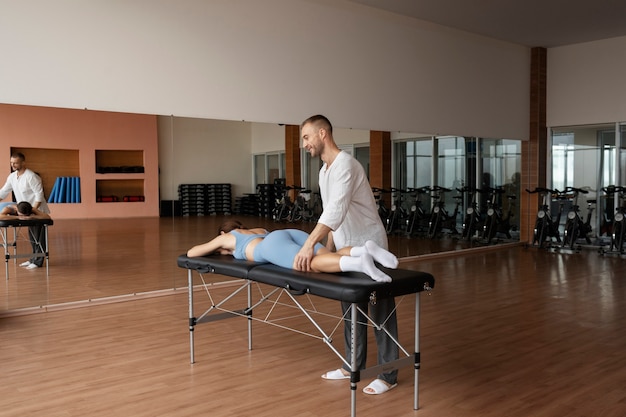 Patient doing physical rehabilitation helped by therapists