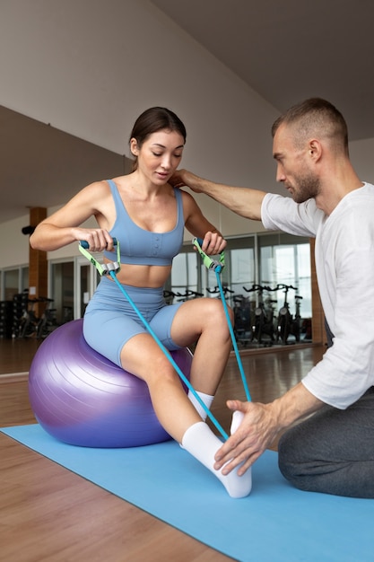 Patient doing physical rehabilitation helped by therapists