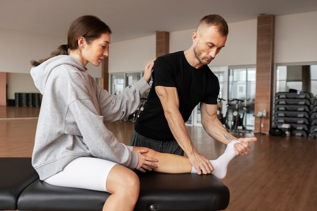 Patient doing physical rehabilitation helped by therapists