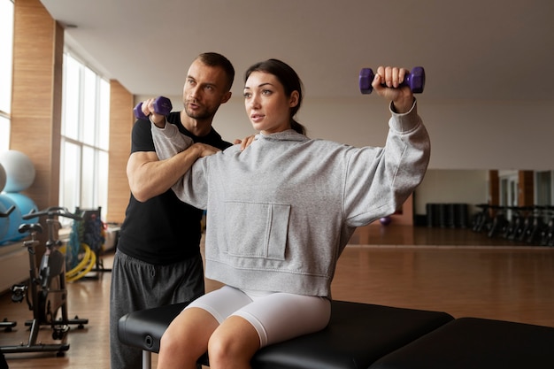 Patient doing physical rehabilitation helped by therapists