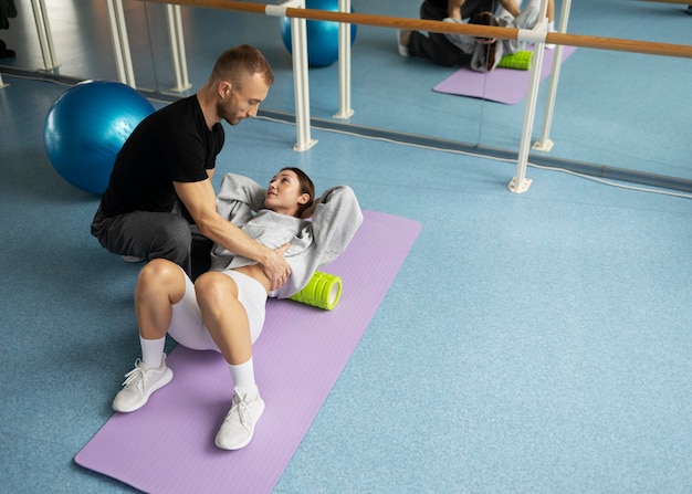 Patient doing physical rehabilitation helped by therapists