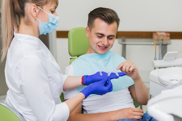 Patient pointing to invisible retainers held by dentist