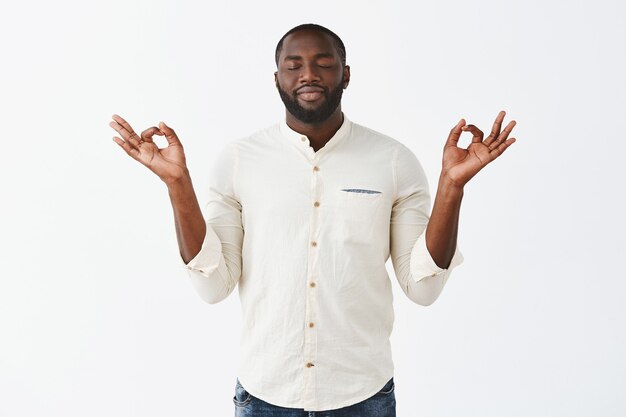 Patient and relaxed young guy posing against the white wall