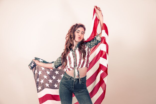 Patriotic girl with the flag of America on a colored wall