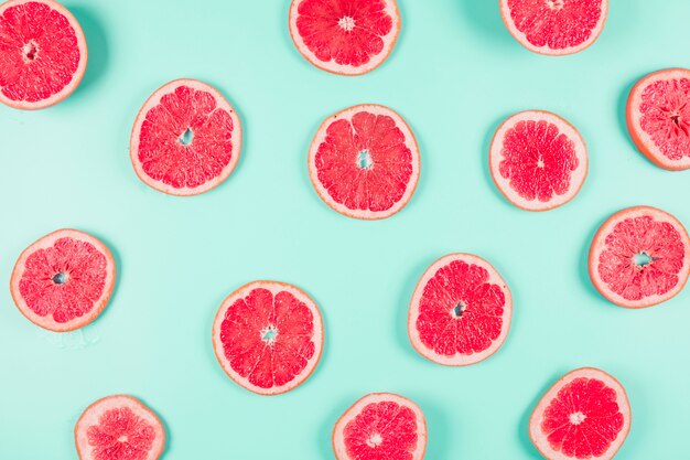 Pattern of grapefruit citrus slices on pastel backdrop
