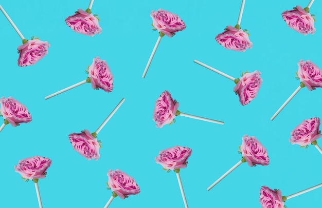Pattern made of pastel pink roses with lollipop sticks minimal summer idea creative candy concept
