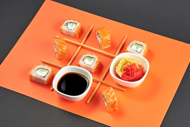 Шаблон суши-роллов филадельфия с лососем на оранжевом фоне. суши разложены, как в игре в крестики-нолики Premium Фотографии