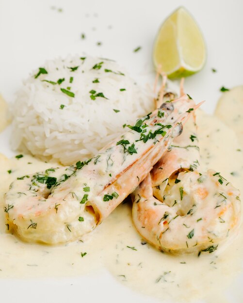 Pawns in creamy sauce with herbs rice and lemon.