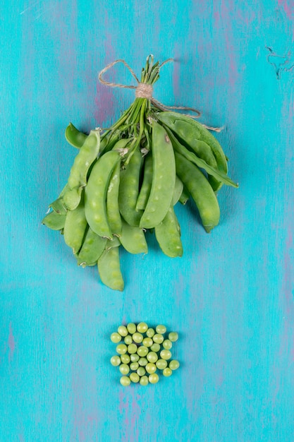 Free photo pea pods on old wooden table