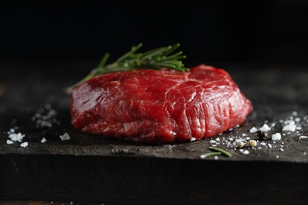 Free photo peace of meat with salt and rosemary on dark board closeup