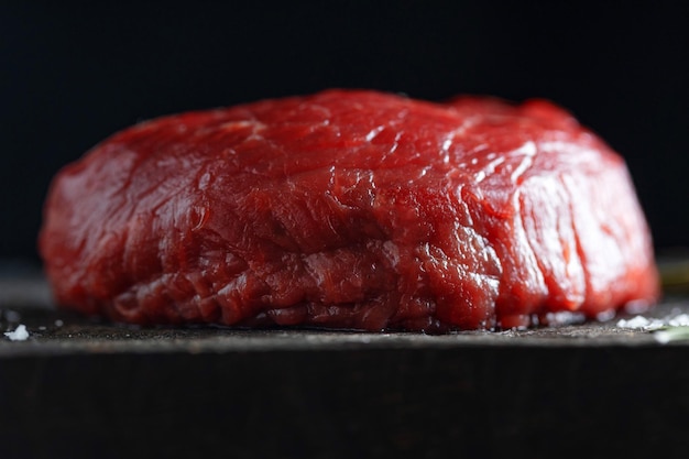 Free photo peace of meat with salt and rosemary on dark board closeup