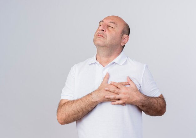 Peaceful casual mature businessman putting hands on heart isolated on white background with copy space