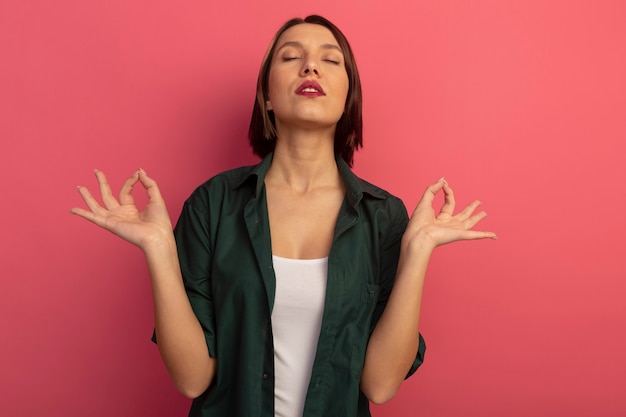 Foto gratuita tranquilla bella donna sta con gli occhi chiusi fingendo di meditare isolato sul muro rosa