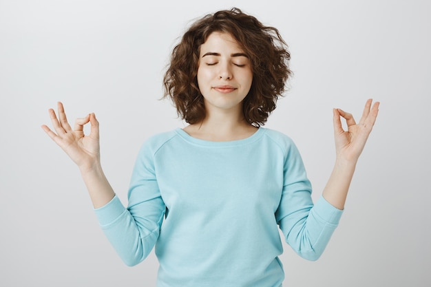 Free photo peaceful and relaxed smiling woman with closed eyes meditating to find nirvana