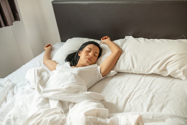 Спящая на кровати мирная безмятежная барышня носит пижаму.