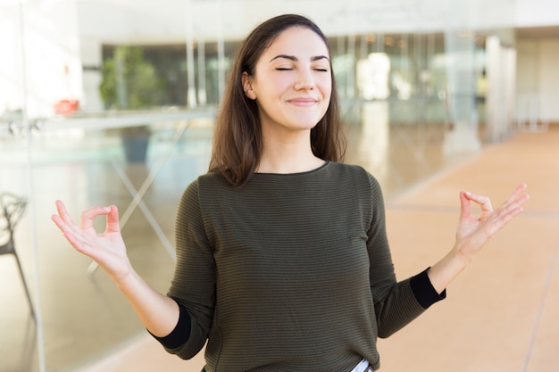 Bella donna sorridente pacifica che fa gesto di zen