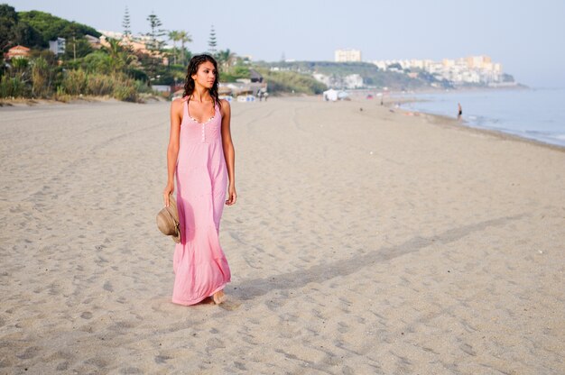 Peaceful woman on the beach with hat in hand