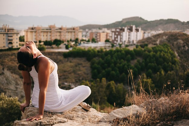 Peaceful woman on rock next to city