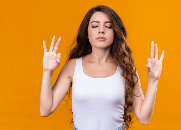 Peaceful young beautiful girl meditating with closed eyes on isolated orange space