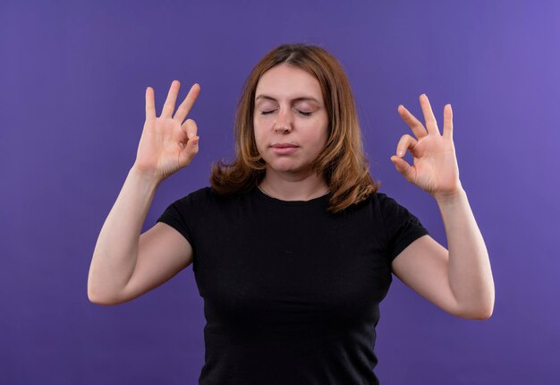 Peaceful young casual woman doing ok sign with closed eyes on isolated purple space