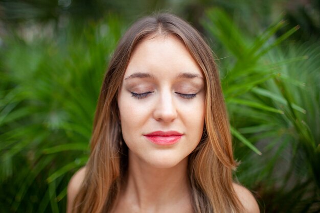 Peaceful young woman with closed eyes enjoying nature sounds