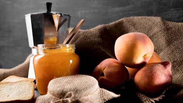 Peach jam in jar with peaches and kettle