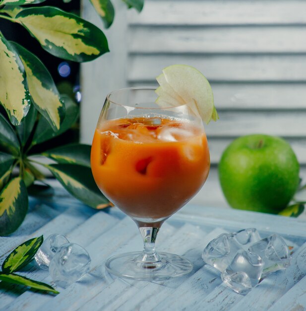 peach juice in glass with ice cubes and apple slices