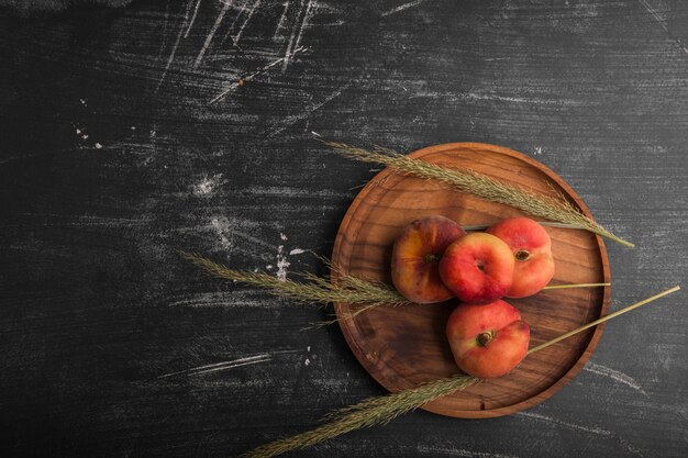 Peaches with herbs or spices on a wooden platter, top view