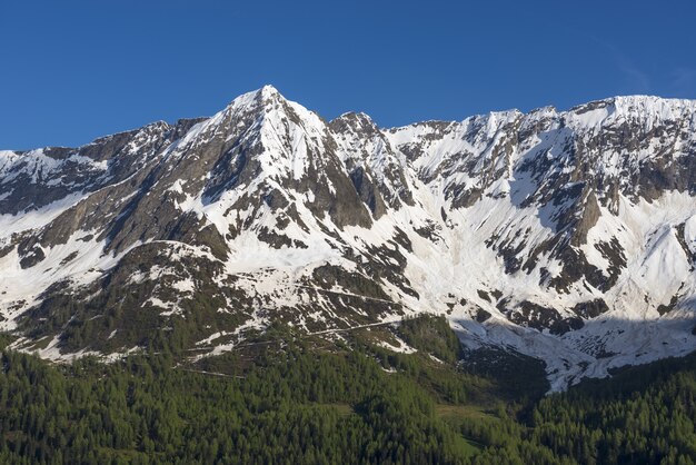 スイス、ティチーノ州の青い空を背景に雪に覆われた山々の頂上