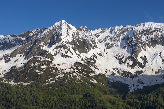 スイス、ティチーノ州の青い空を背景に雪に覆われた山々の頂上