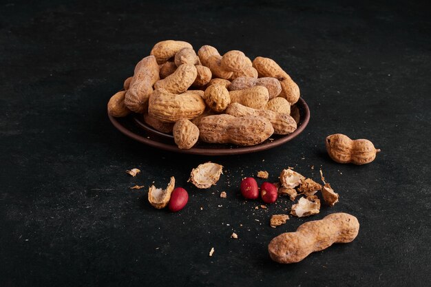 Peanut shells in ceramic saucer on black surface. 