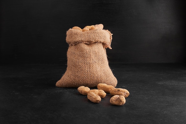 Free photo peanut shells out of a rustic parcel on black background.