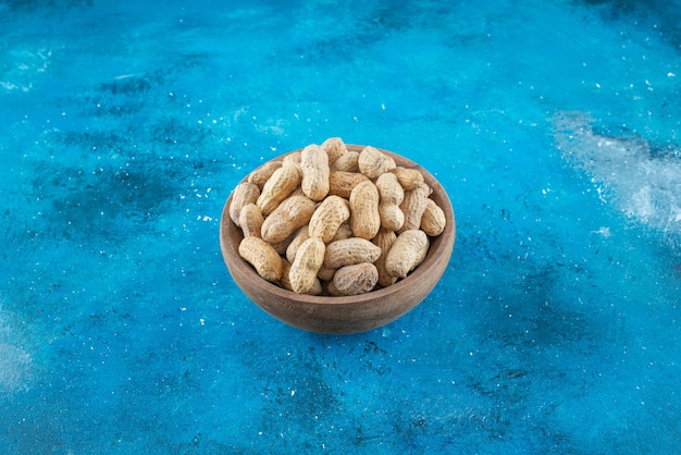 Peanuts in shell in a bowl , on the blue table. 