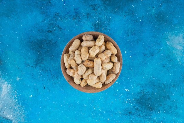 Free photo peanuts in shell in a bowl , on the blue table.