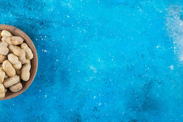 Peanuts in shell in a bowl , on the blue table. 