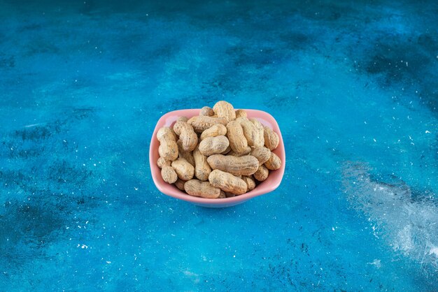 Peanuts in shell in a plate , on the blue table. 