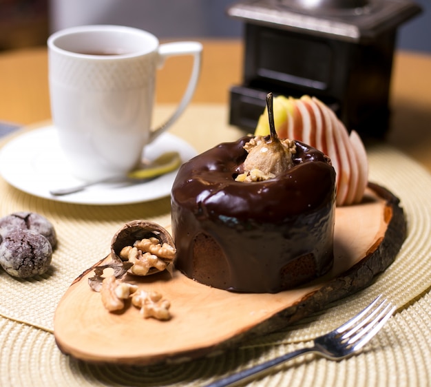 Грушевый пирог на деревянной доске с грецкими орехами, шоколадом и свежими фруктами, вид сбоку