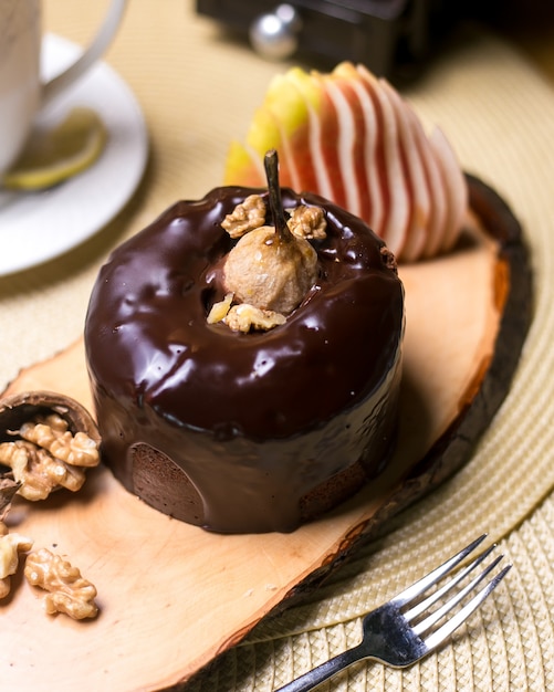 Грушевый пирог на деревянной доске с грецкими орехами, шоколадом и свежими фруктами, вид сбоку