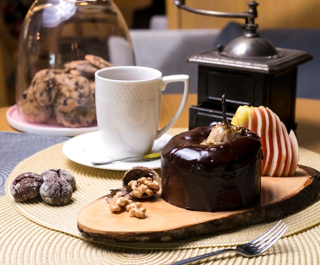 Pear cake on the wooden board with walnuts chocolate and fresh fruits tea side view