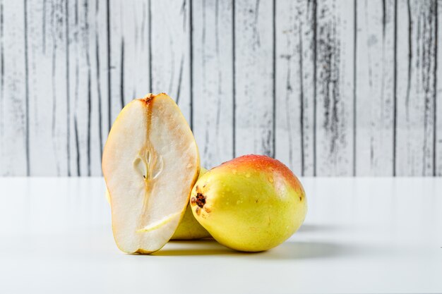 Pear and half on wooden and white background.