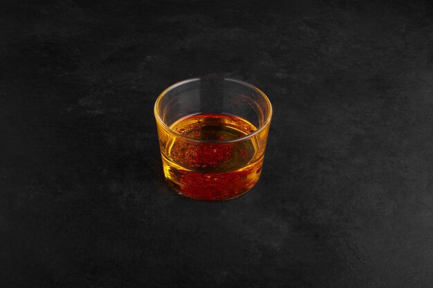 Грушевый сок в стеклянной чашке на черной поверхности.